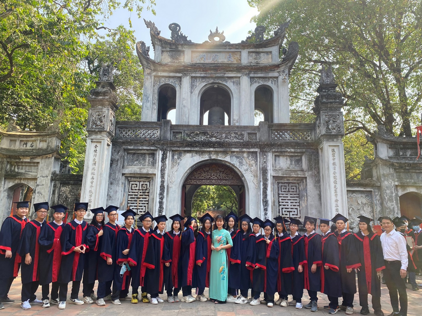 A group of people in graduation gowns and caps standing in front of a building

Description automatically generated with medium confidence