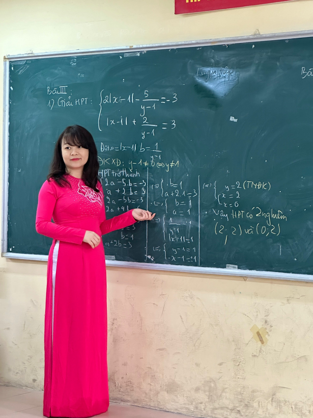 A person in a pink dress standing in front of a chalkboard

Description automatically generated